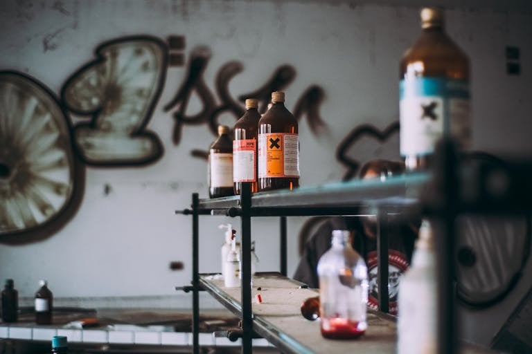 Discover an abandoned industrial room featuring shelves of toxic chemical bottles and graffiti walls.